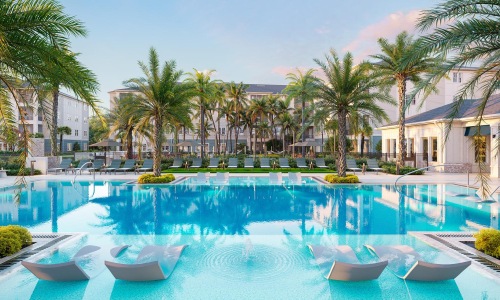 a pool with palm trees and a building in the background